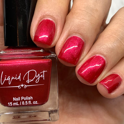 Hand with fingernails painted with a cranberry shimmer shade