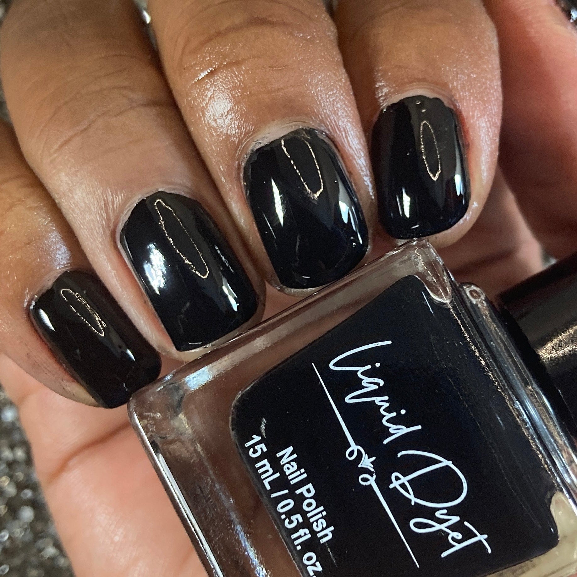 Picture of fingernails painted in a sleek black vegan nail polish