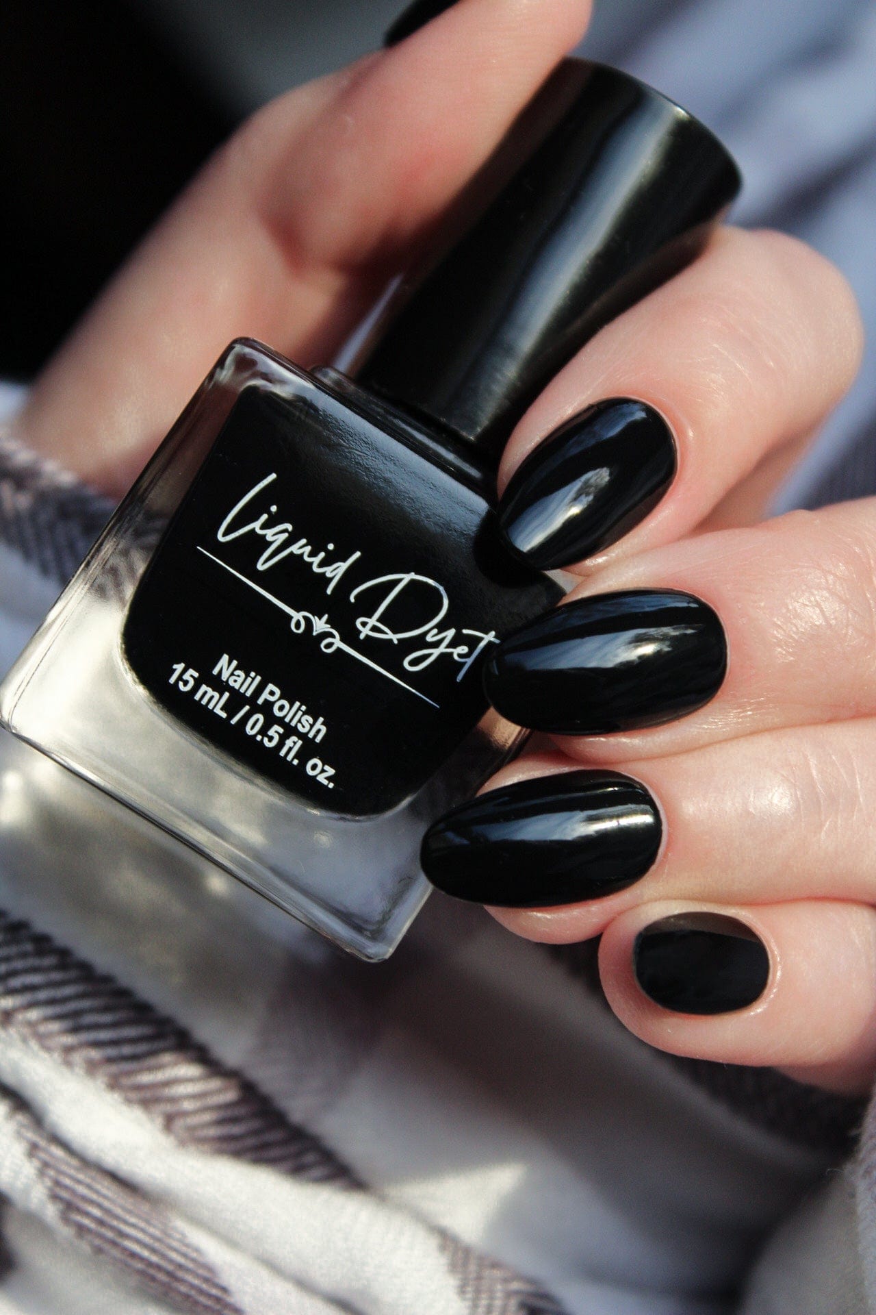 Picture of fingernails painted in a sleek black vegan nail polish